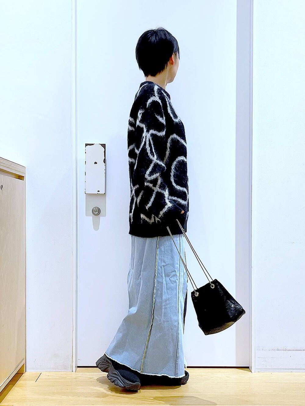 ブルー系のデニムスカート、ブラック系のブーツ、ブラック系のショルダーバッグを着用したレディースの冬コーディネートの4枚目の写真