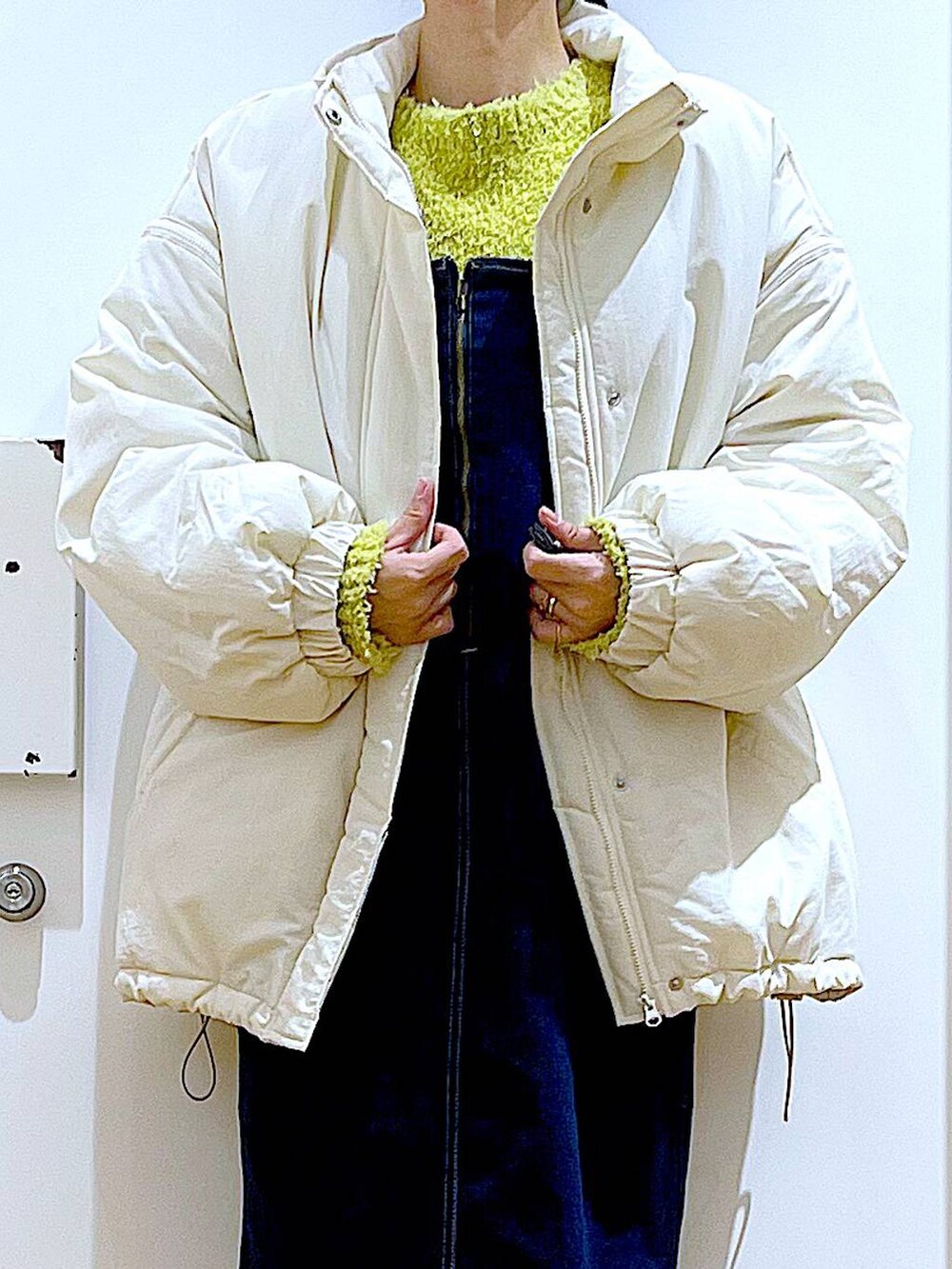 グリーン系のニット/セーター、ブルー系のジャンパースカート、ホワイト系のボディバッグ/ウエストポーチを着用したレディースの冬コーディネートの7枚目の写真