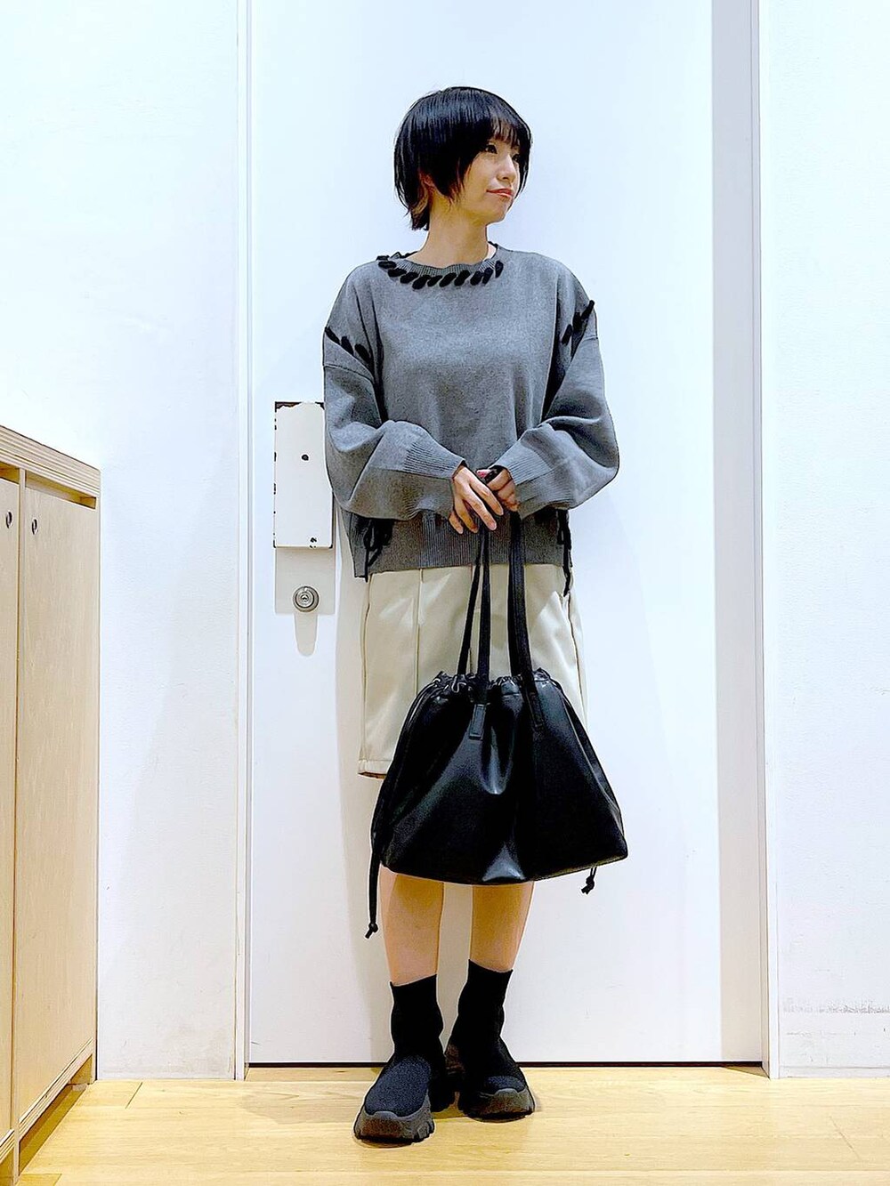 ブラック系のトートバッグ、ブラック系のブーツ、グレー系のニット/セーターを着用したレディースの冬コーディネートの2枚目の写真