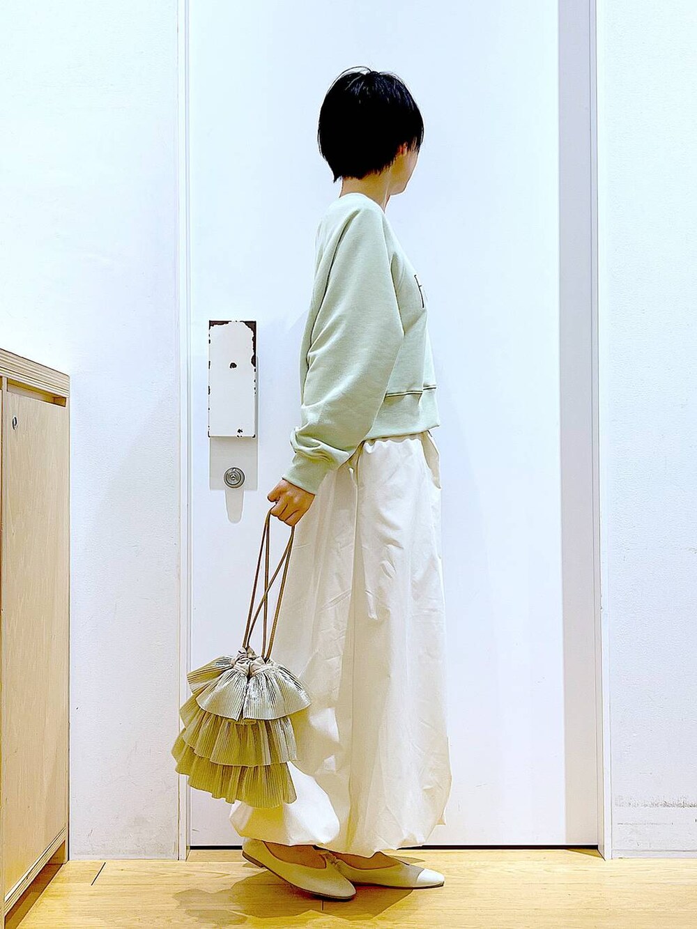 ホワイト系のパンプス、ベージュ系のショルダーバッグ、グリーン系のスウェットを着用したレディースの春コーディネートの4枚目の写真