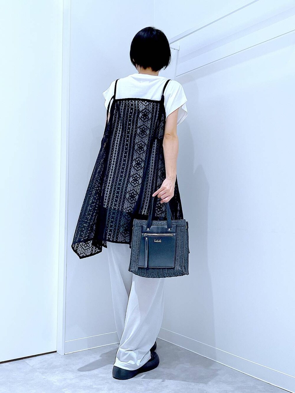 ブラック系のショルダーバッグ、ブラック系のサンダル、ホワイト系のTシャツ/カットソーを着用したレディースの夏コーディネートの5枚目の写真