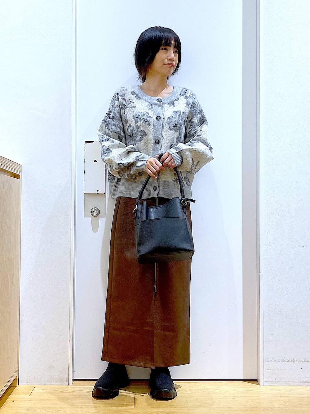 ブラウン系のスカート、ブラック系のショルダーバッグ、ブラック系のブーツを着用したレディースの冬コーディネートの2枚目の写真