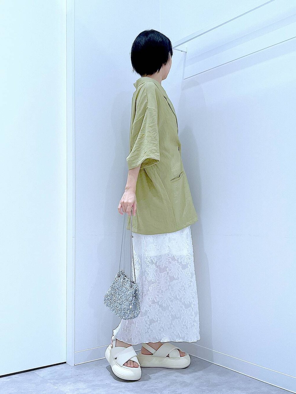シルバー系のショルダーバッグ、ホワイト系のサンダル、グリーン系のテーラードジャケットを着用したレディースの夏コーディネートの4枚目の写真