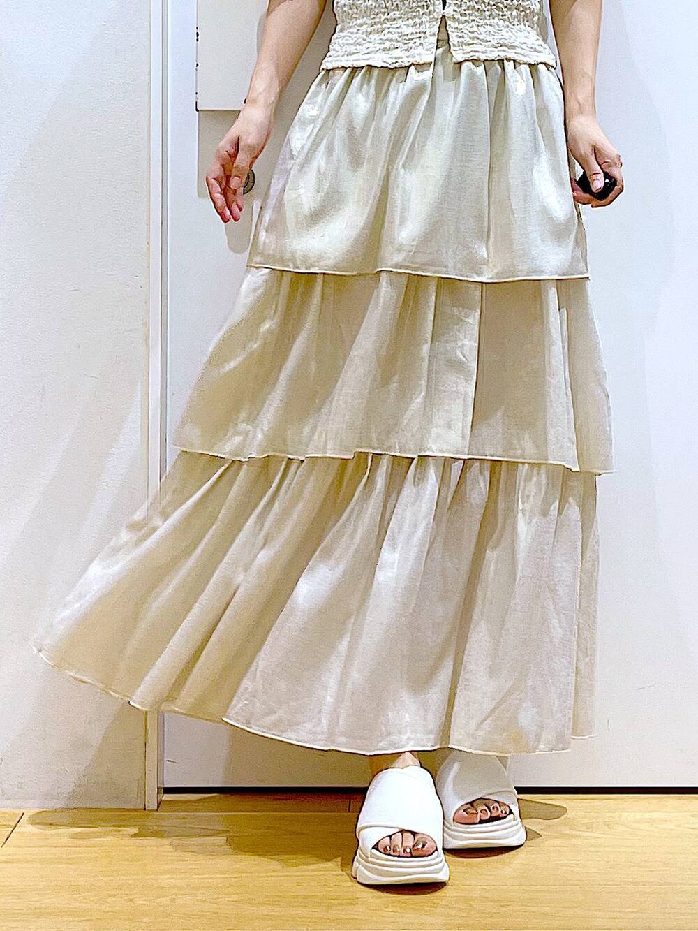 ホワイト系のサンダル、グレー系のトートバッグ、ゴールド系のスカートを着用したレディースの夏コーディネートの8枚目の写真