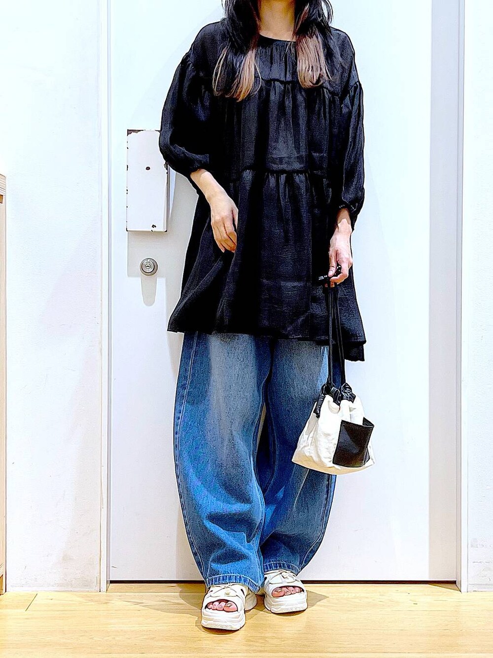 ホワイト系のショルダーバッグ、ブルー系のデニムパンツ、ホワイト系のサンダルを着用したレディースの夏コーディネートの6枚目の写真