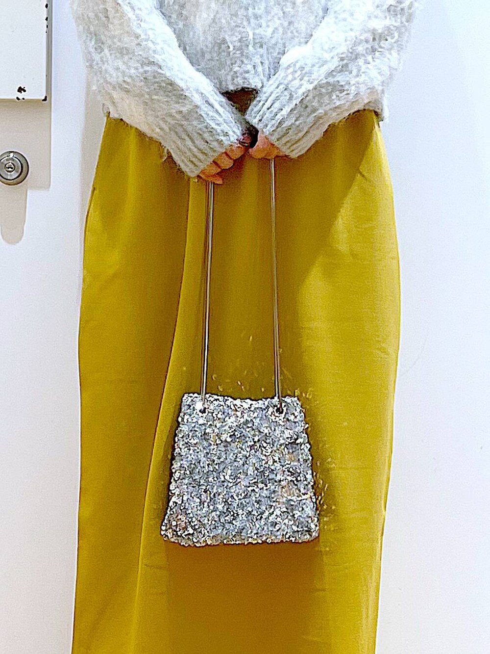 ブラック系のブーツ、イエロー系のスカート、その他のショルダーバッグを着用したレディースの冬コーディネートの9枚目の写真