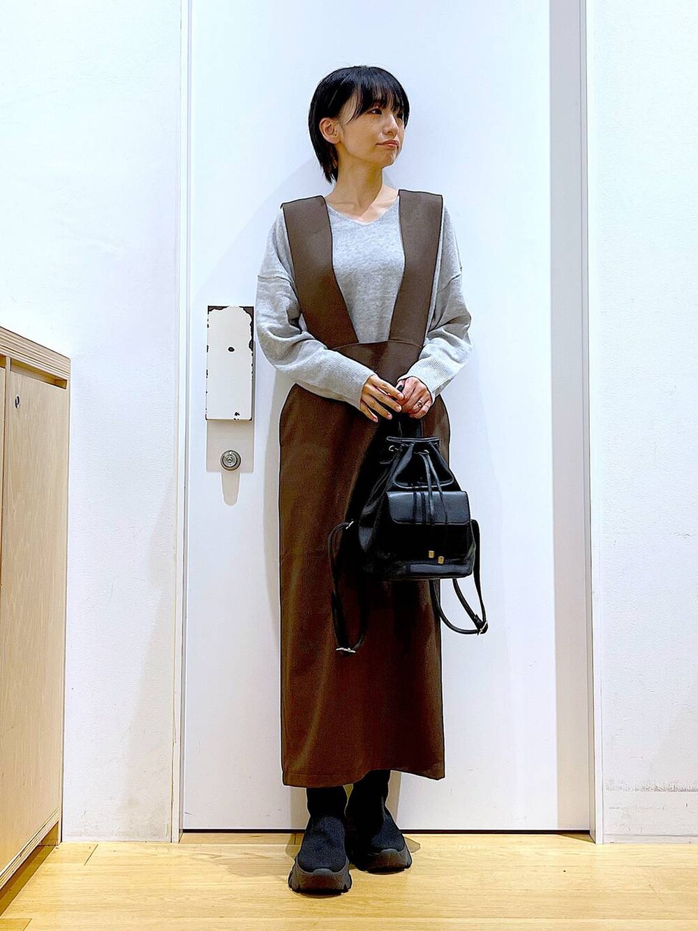 グレー系のニット/セーター、ブラック系のバックパック/リュック、ブラック系のブーツを着用したレディースの冬コーディネートの2枚目の写真