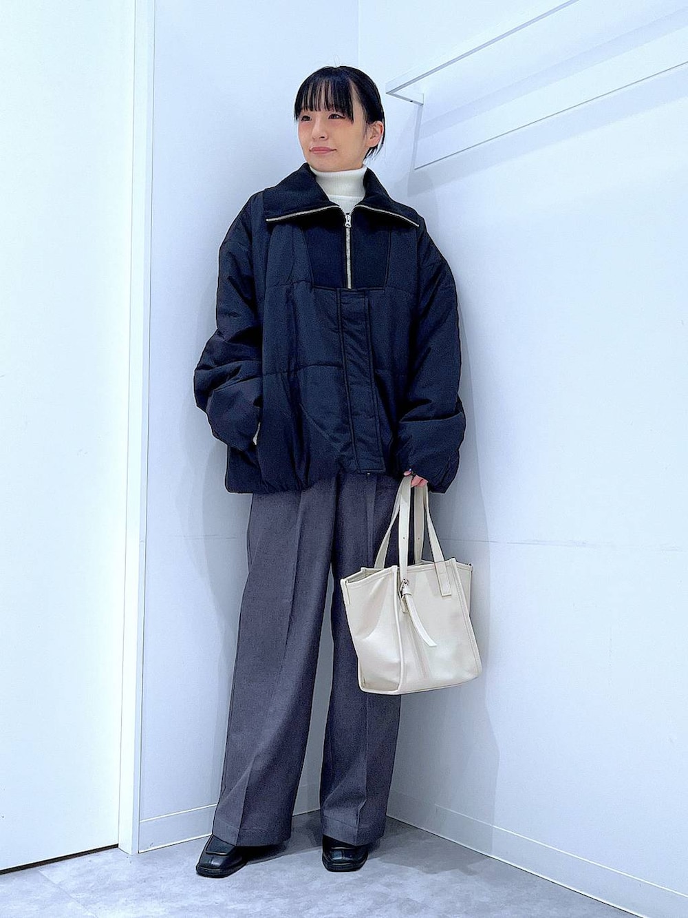 ブラック系のブルゾン、ブラック系のブーツ、グレー系のスラックスを着用したレディースの冬コーディネートの2枚目の写真