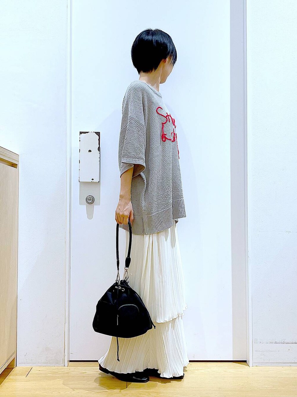 ブラック系のパンプス、ホワイト系のスカート、グレー系のニット/セーターを着用したレディースの春コーディネートの4枚目の写真