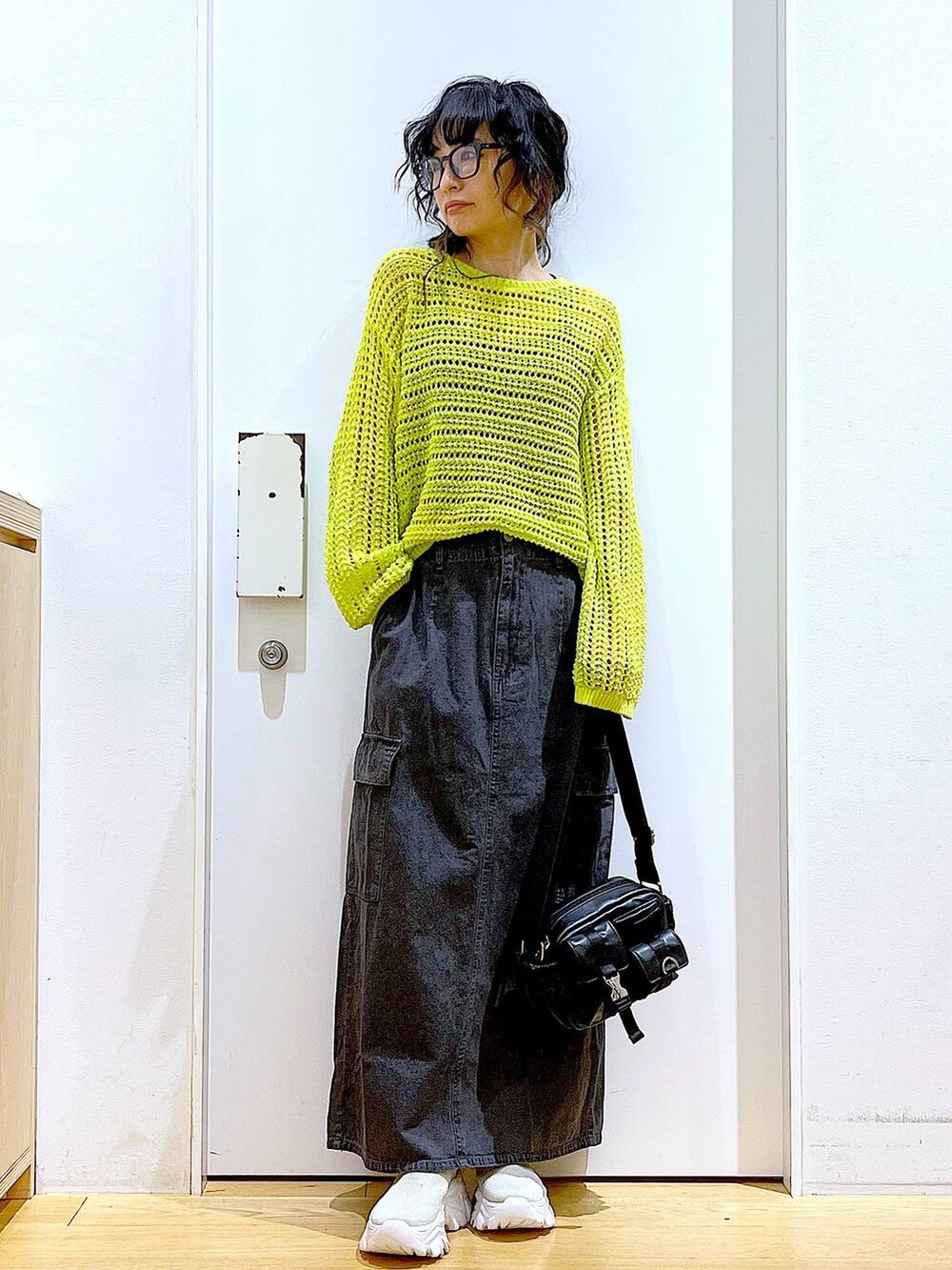 グレー系のデニムスカート、ベージュ系のスニーカー、ブラック系のショルダーバッグを着用したレディースの春コーディネートの2枚目の写真