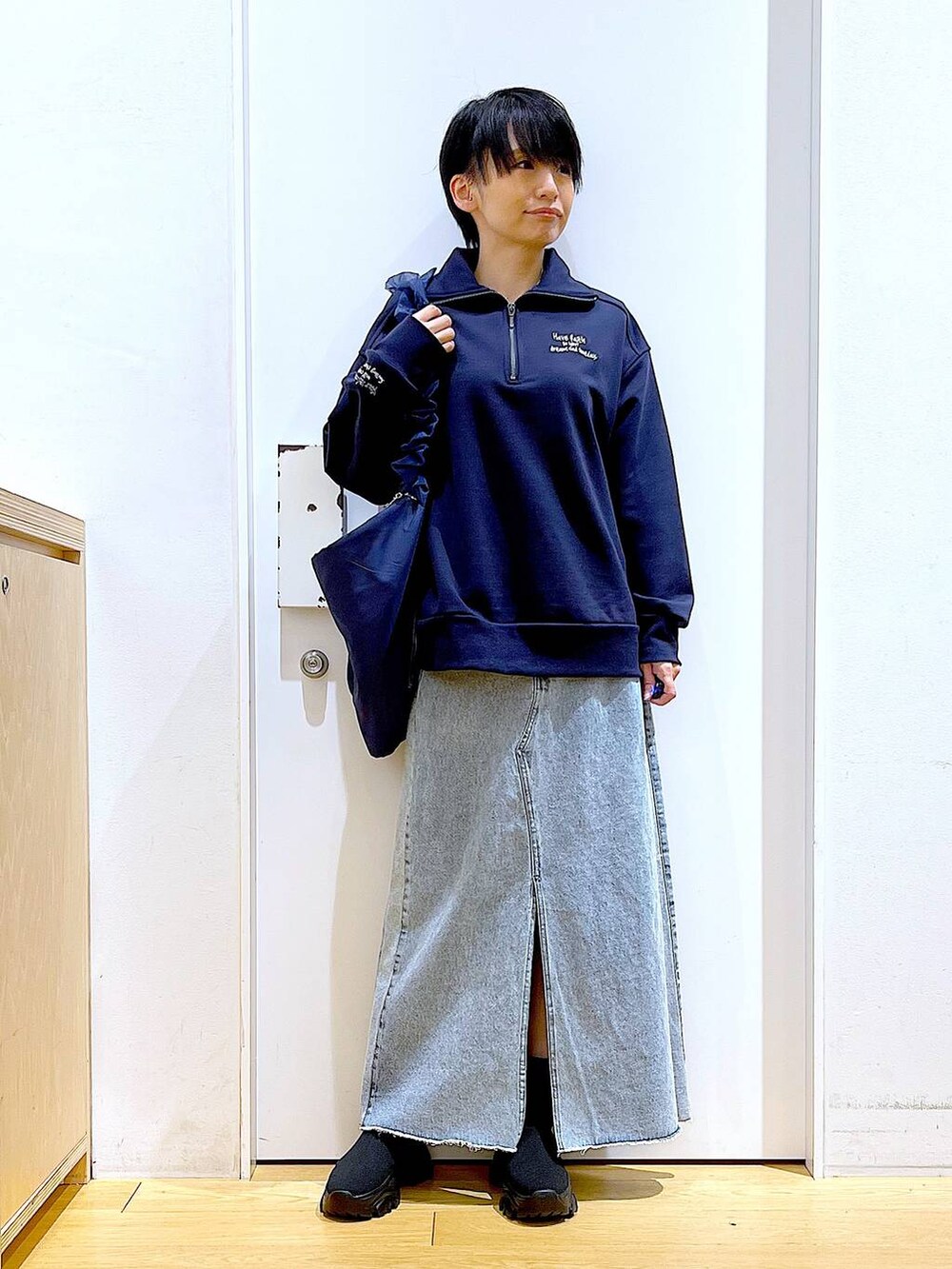 ブルー系のショルダーバッグ、ブラック系のブーツ、ブルー系のデニムスカートを着用したレディースの春コーディネートの2枚目の写真