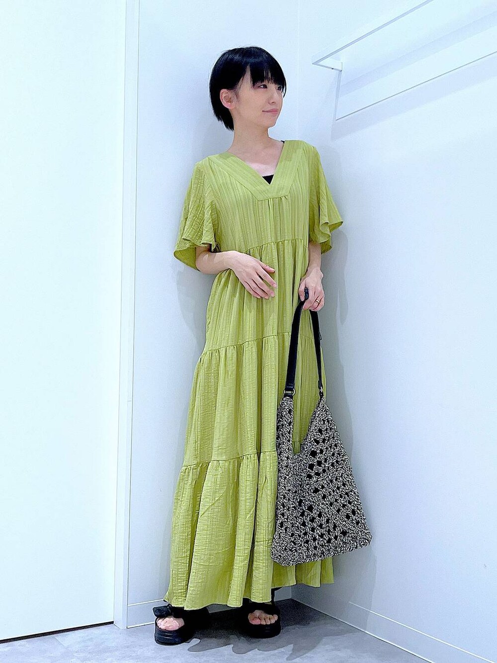 ブラック系のトートバッグ、ブラック系のサンダル、グリーン系のワンピースを着用したレディースの夏コーディネートの2枚目の写真