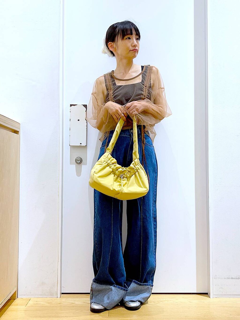 イエロー系のハンドバッグ、シルバー系のローファー、ブルー系のデニムパンツを着用したレディースの秋コーディネートの2枚目の写真