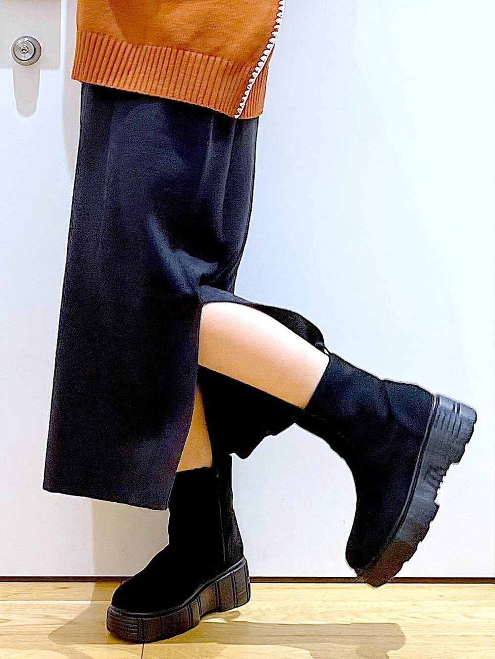 グレー系のスカート、オレンジ系のニット/セーター、ブラウン系のクラッチバッグを着用したレディースの冬コーディネートの8枚目の写真