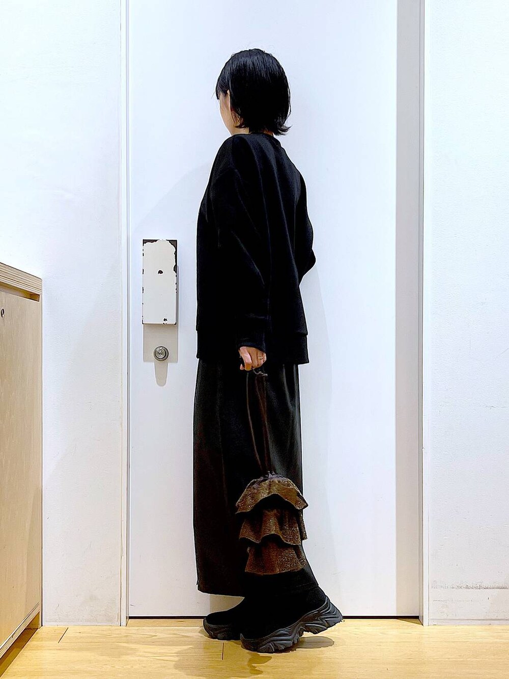 ブラック系のスカート、ブラック系のブーツ、ブラウン系のショルダーバッグを着用したレディースの冬コーディネートの3枚目の写真