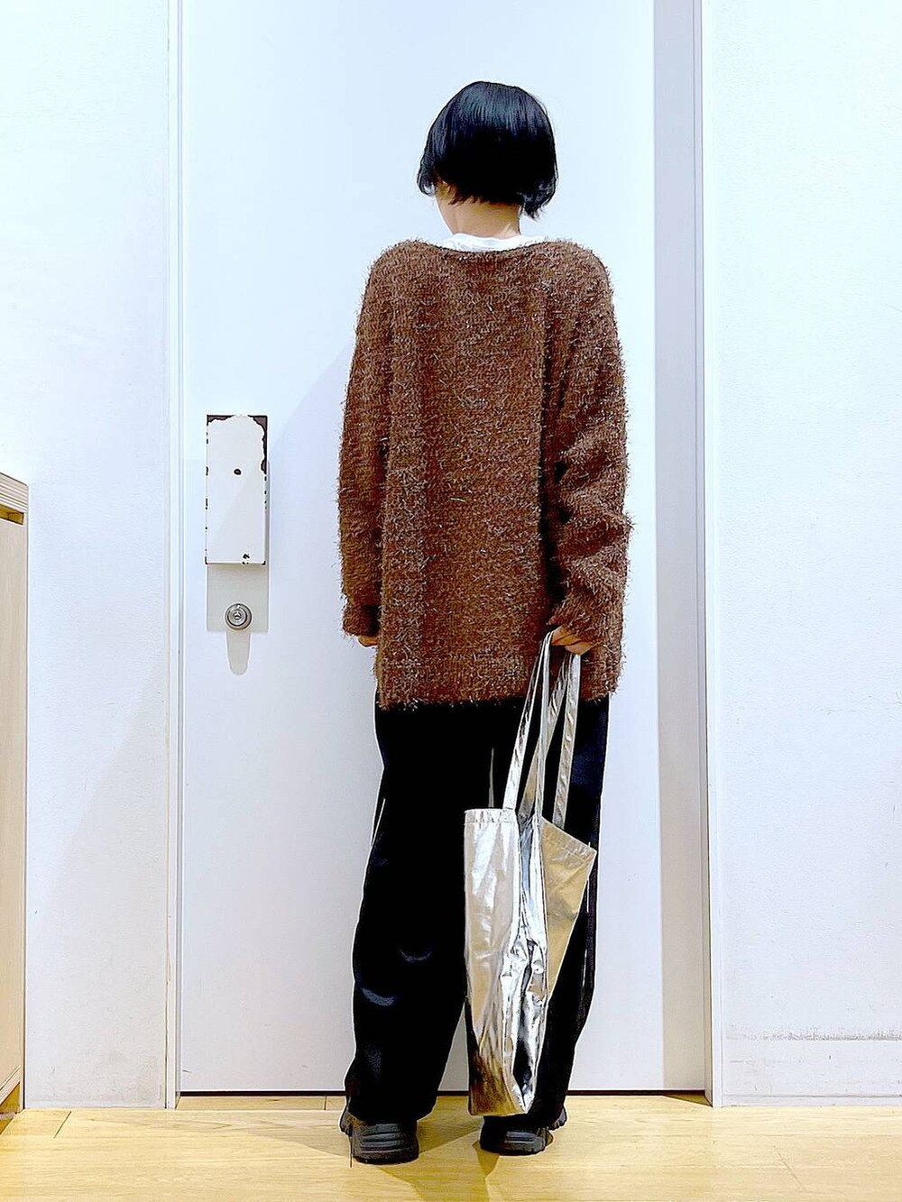シルバー系のトートバッグ、ブラック系のスラックス、ホワイト系のTシャツ/カットソーを着用したレディースの秋コーディネートの5枚目の写真