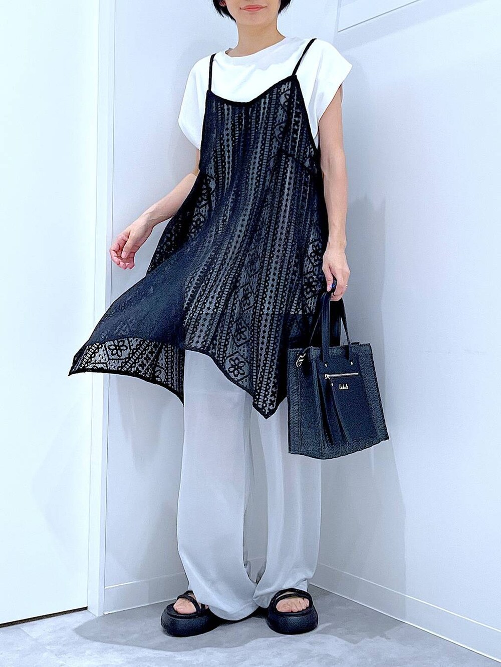 ブラック系のショルダーバッグ、ブラック系のサンダル、ホワイト系のTシャツ/カットソーを着用したレディースの夏コーディネートの6枚目の写真