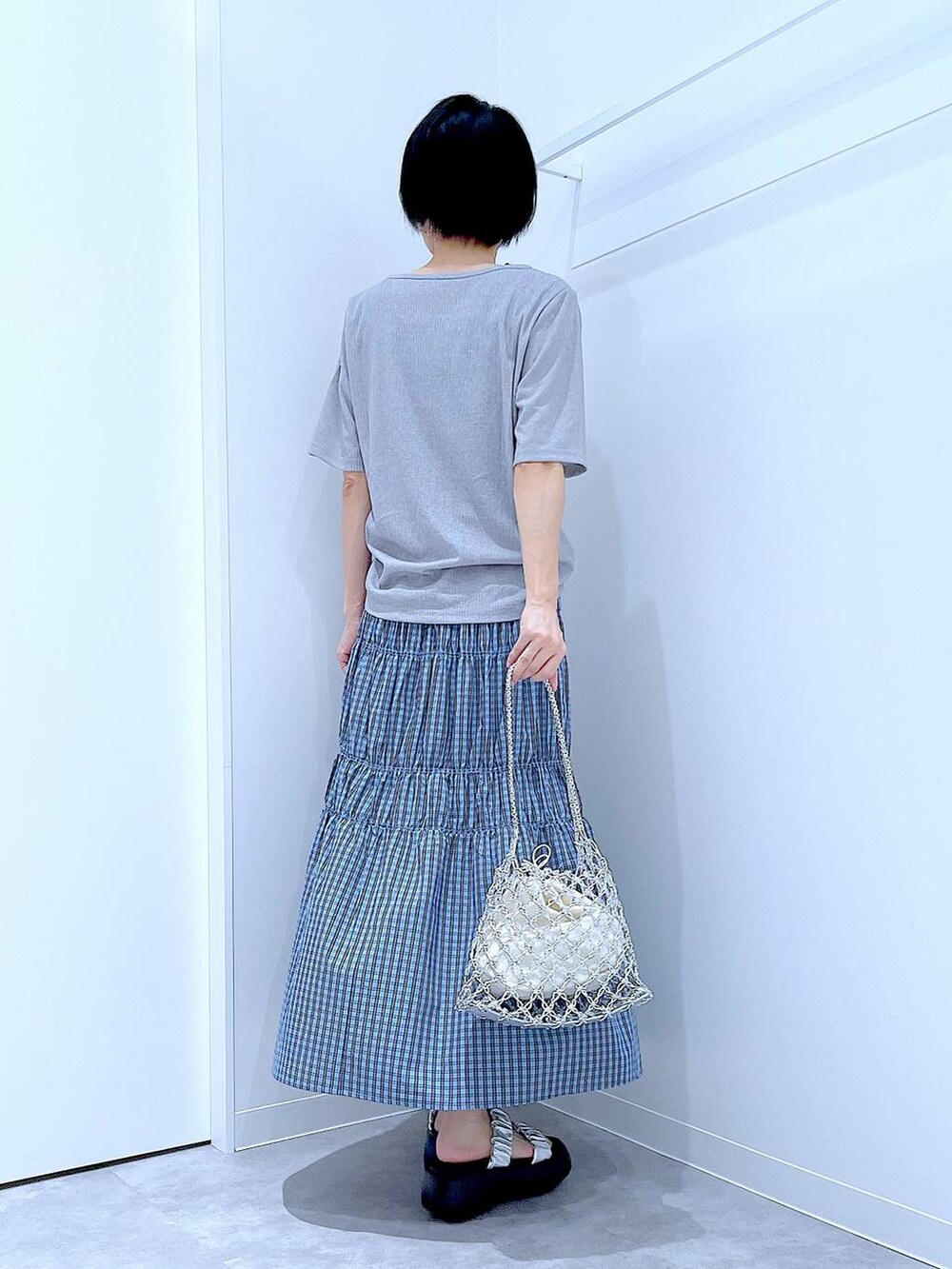 シルバー系のかごバッグ、シルバー系のサンダル、ブルー系のスカートを着用したレディースの夏コーディネートの5枚目の写真