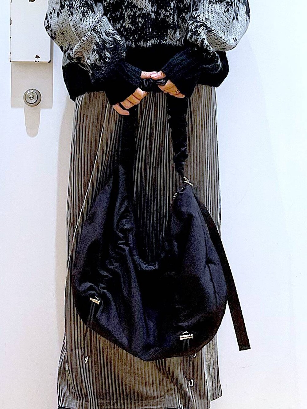 ブラック系のショルダーバッグ、グレー系のスカート、ブラック系のブーツを着用したレディースの冬コーディネートの9枚目の写真