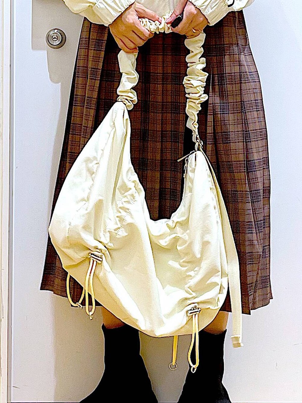 ホワイト系のショルダーバッグ、ベージュ系のブルゾン、ブラック系のブーツを着用したレディースの秋コーディネートの9枚目の写真