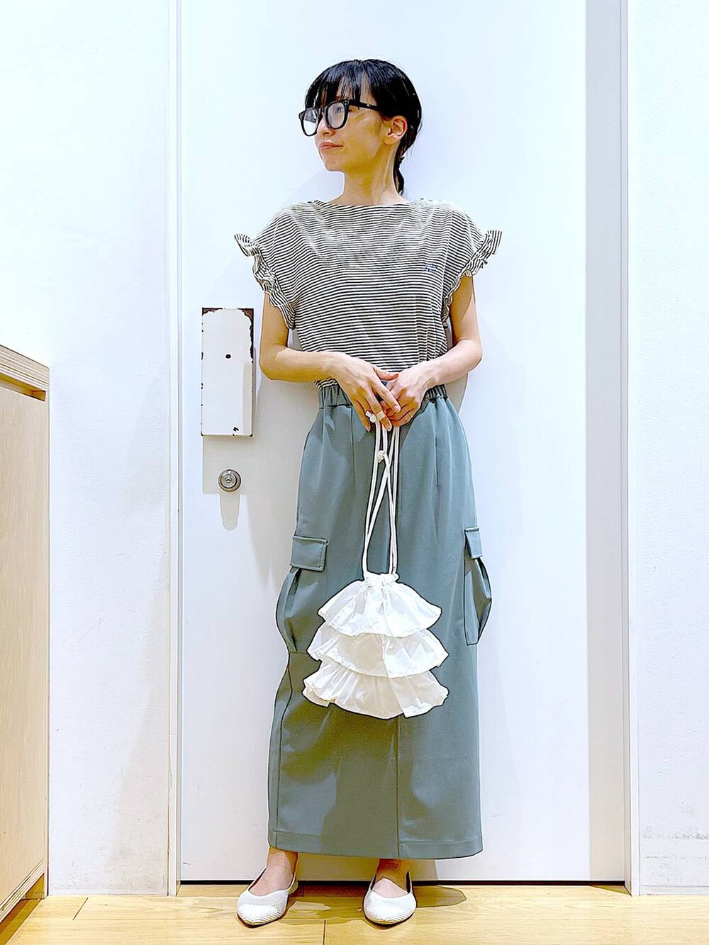 ホワイト系のショルダーバッグ、ホワイト系のパンプス、グリーン系のスカートを着用したレディースの春コーディネートの2枚目の写真