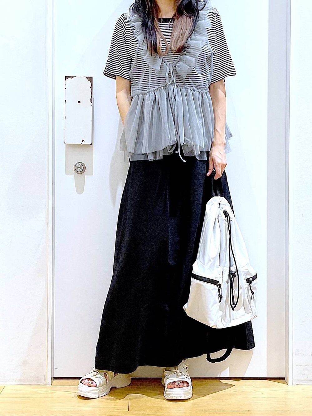 ホワイト系のショルダーバッグ、ホワイト系のサンダル、ブラック系のスカートを着用したレディースの夏コーディネートの6枚目の写真