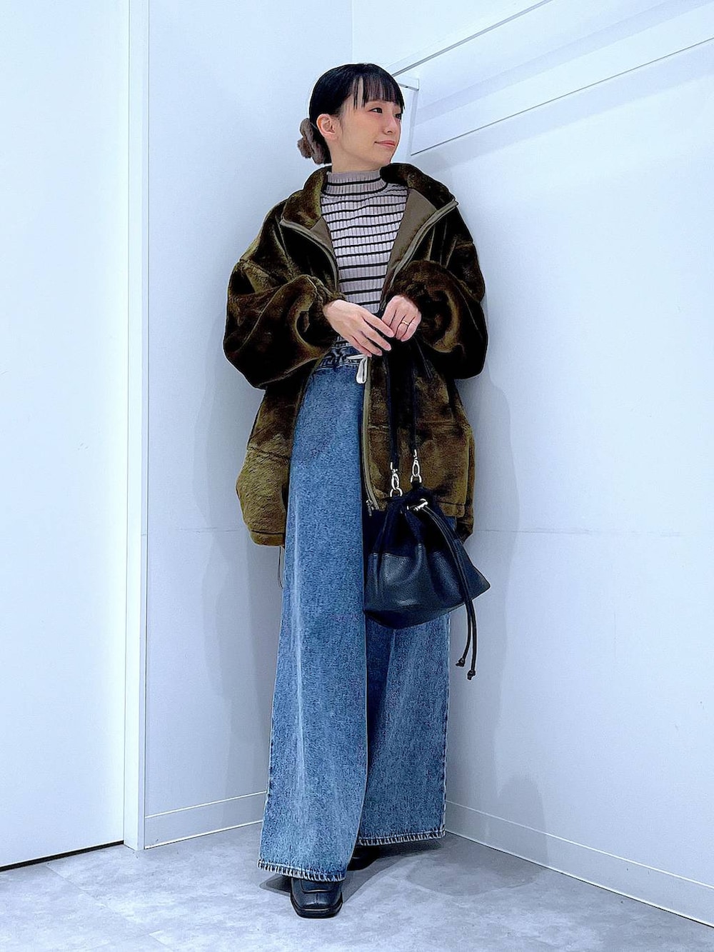 グリーン系のブルゾン、その他のニット/セーター、ブルー系のデニムパンツを着用したレディースの冬コーディネートの2枚目の写真