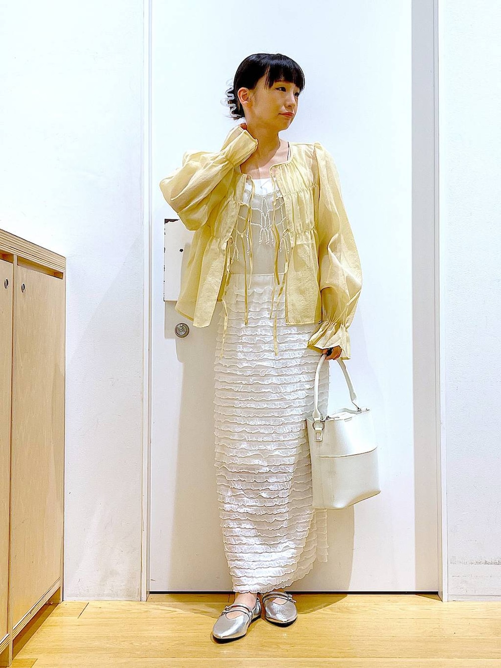 ホワイト系のベスト、ホワイト系のショルダーバッグ、ホワイト系のスカートを着用したレディースの秋コーディネートの2枚目の写真