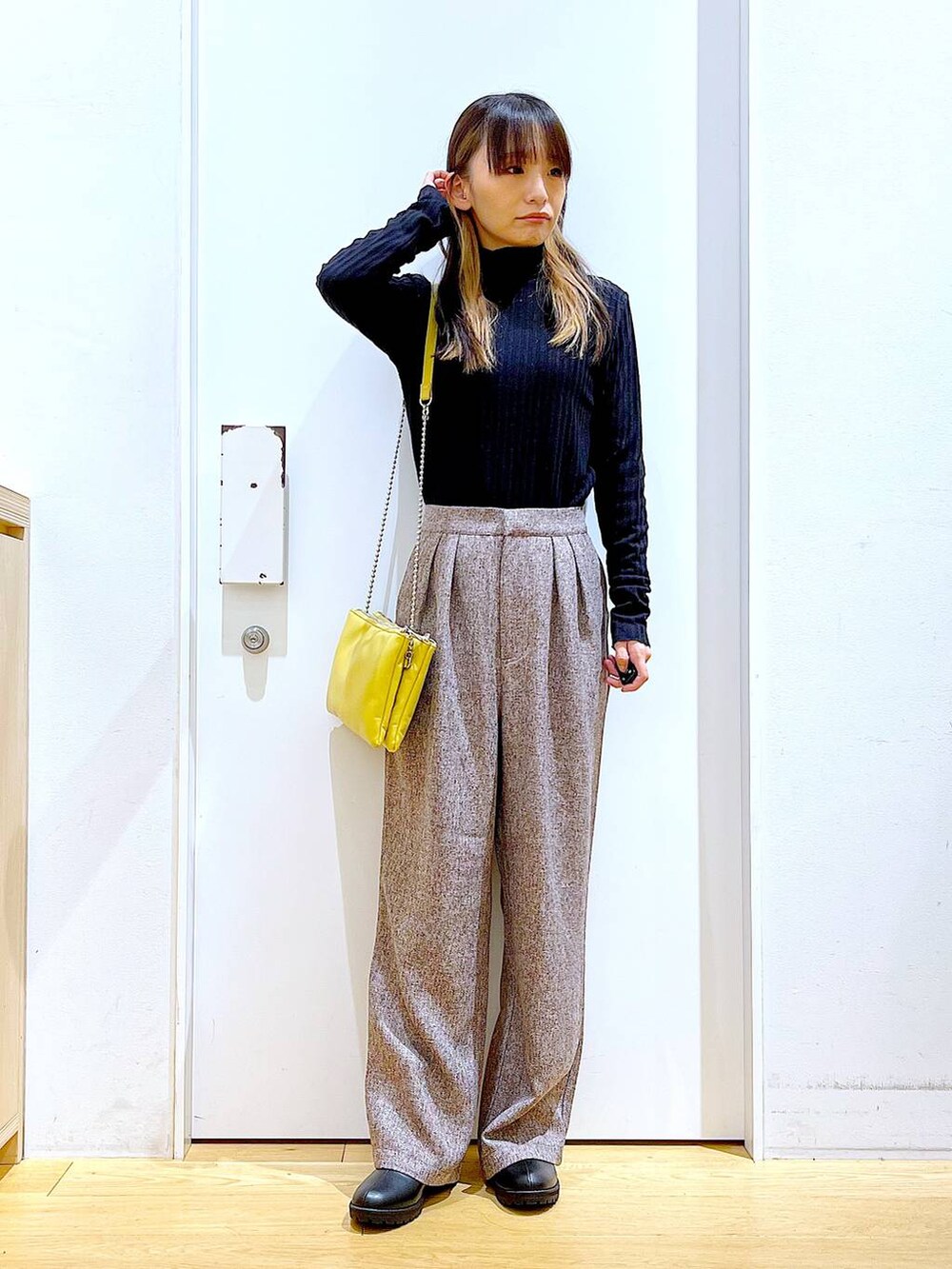 イエロー系のショルダーバッグ、ブラック系のブーツ、ブラウン系のその他パンツを着用したレディースの冬コーディネートの2枚目の写真