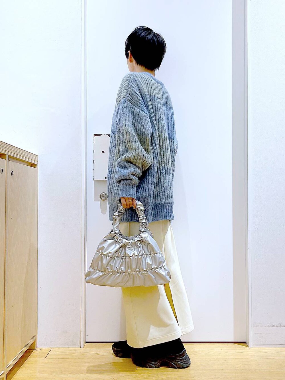 ブルー系のニット/セーター、ブラック系のブーツ、シルバー系のショルダーバッグを着用したレディースの冬コーディネートの3枚目の写真