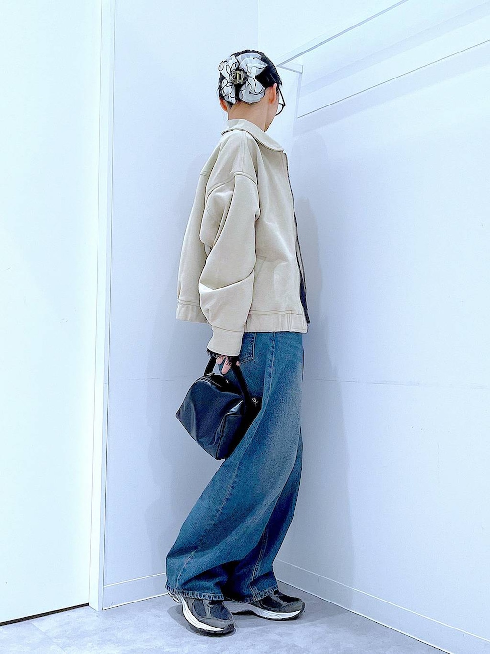 ブルー系のデニムパンツ、ブラック系のショルダーバッグ、ベージュ系のブルゾンを着用したレディースの春コーディネートの4枚目の写真