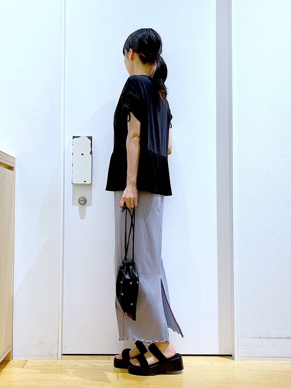 パープル系のスカート、ブラック系のショルダーバッグ、ブラック系のサンダルを着用したレディースの夏コーディネートの3枚目の写真