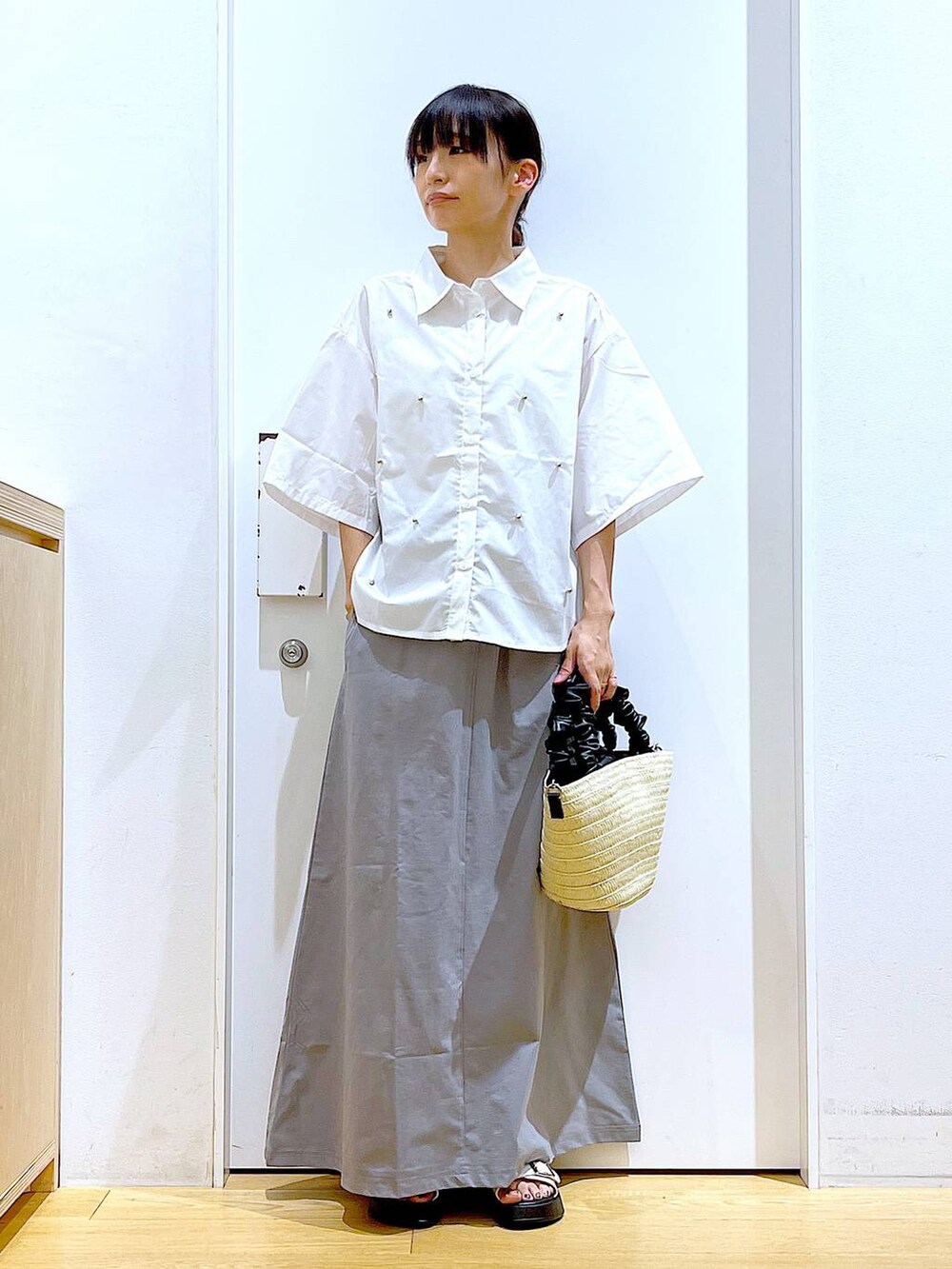 ホワイト系のサンダル、ホワイト系のショルダーバッグ、グレー系のスカートを着用したレディースの夏コーディネートの2枚目の写真