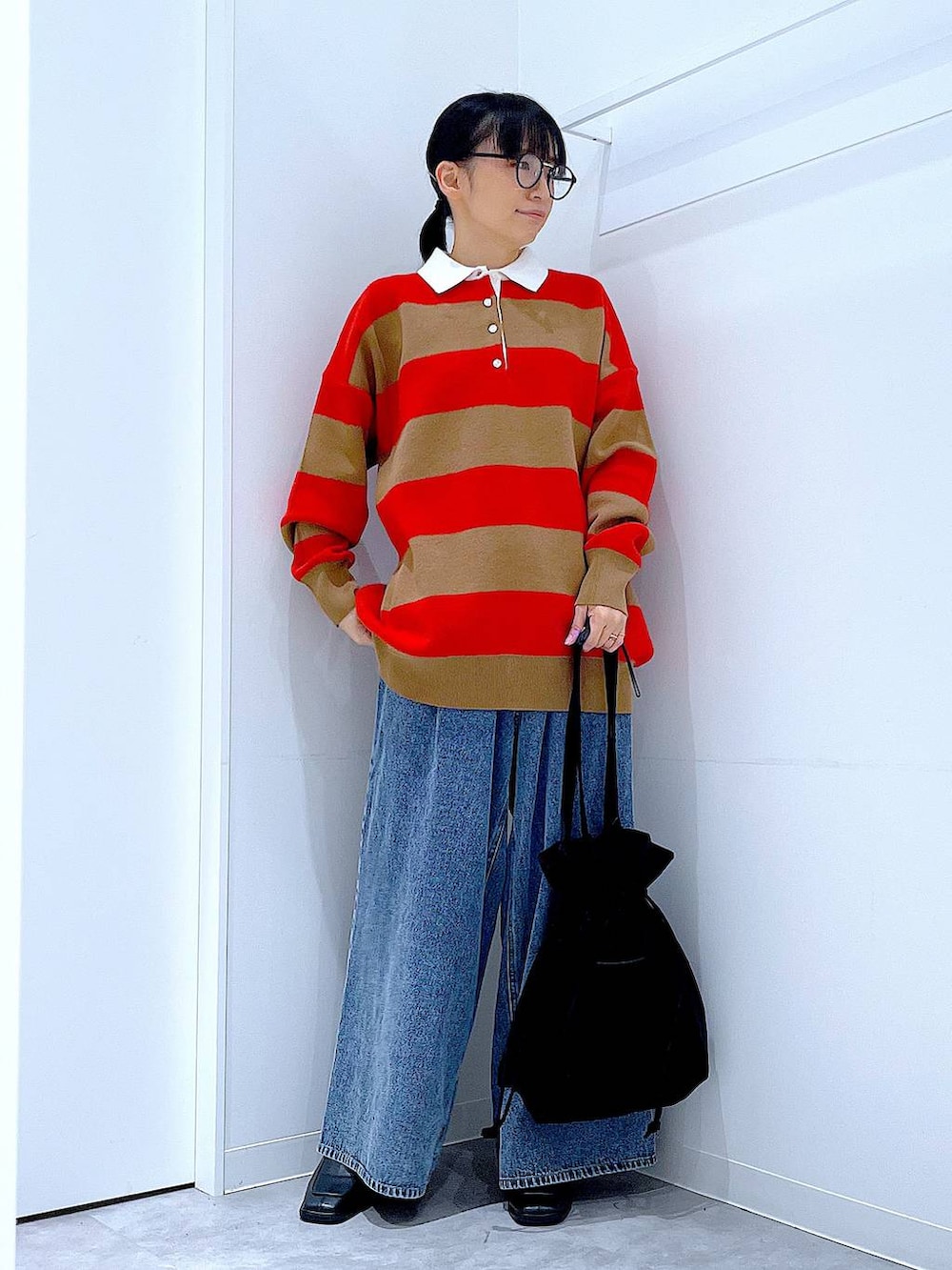 ブラック系のトートバッグ、レッド系のニット/セーター、ブルー系のデニムパンツを着用したレディースの冬コーディネートの2枚目の写真