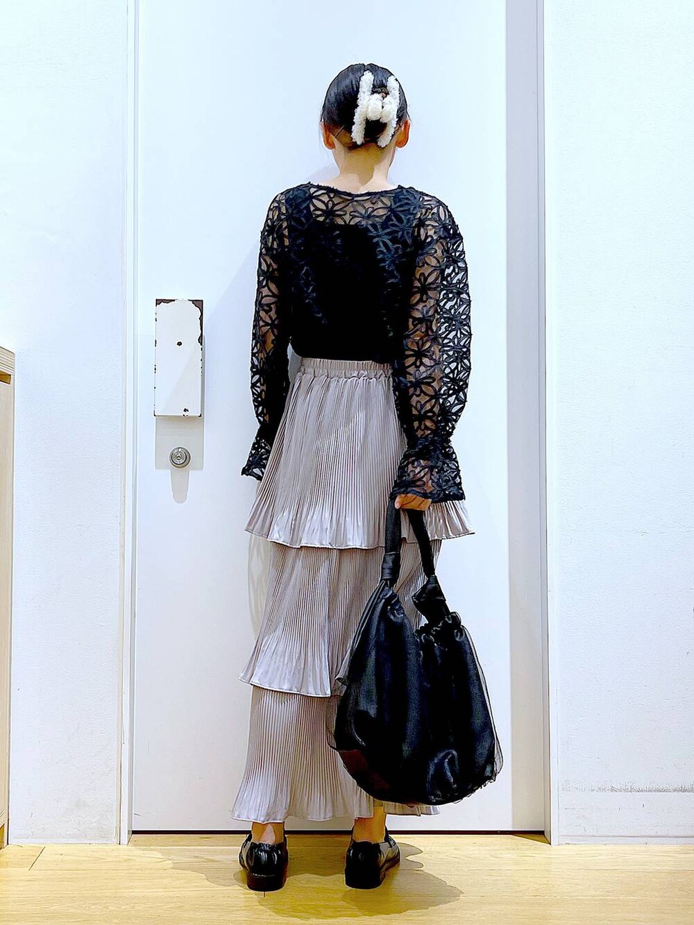 グレー系のスカート、ブラック系のトートバッグ、ブラック系のローファーを着用したレディースの秋コーディネートの5枚目の写真