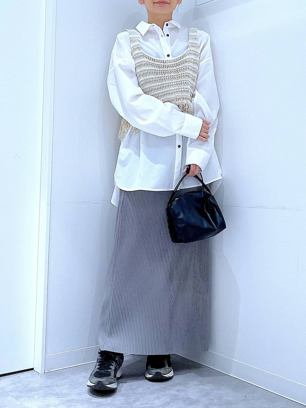 ブラック系のショルダーバッグ、ベージュ系のベスト、グレー系のスカートを着用したレディースの春コーディネートの6枚目の写真