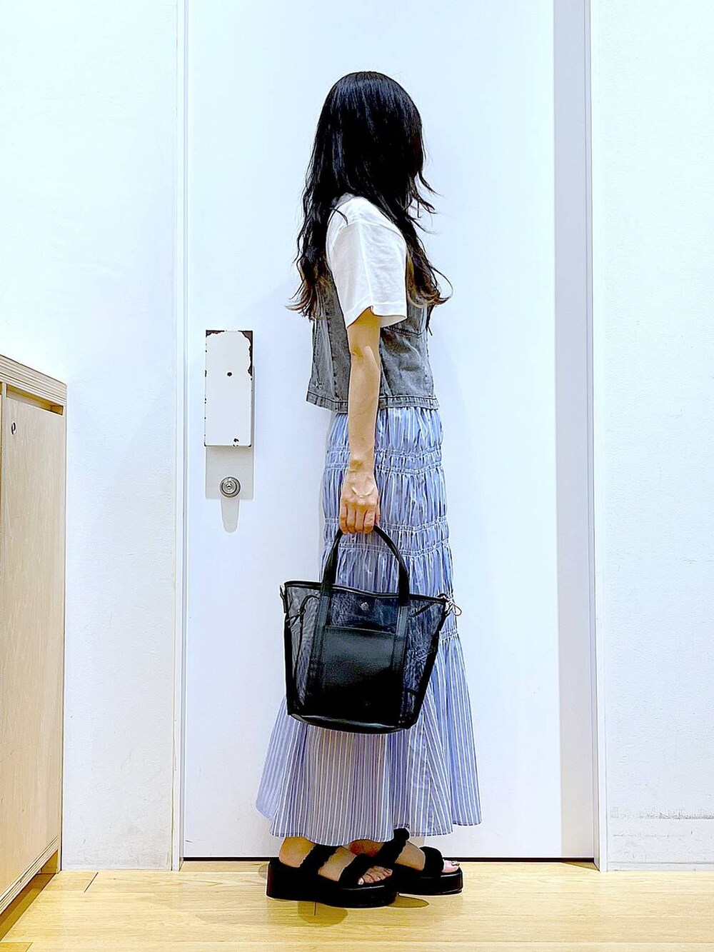 ブラック系のサンダル、ブラック系のトートバッグ、グレー系のベストを着用したレディースの夏コーディネートの4枚目の写真