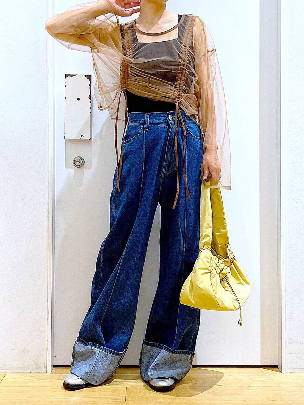 イエロー系のハンドバッグ、シルバー系のローファー、ブルー系のデニムパンツを着用したレディースの秋コーディネートの6枚目の写真