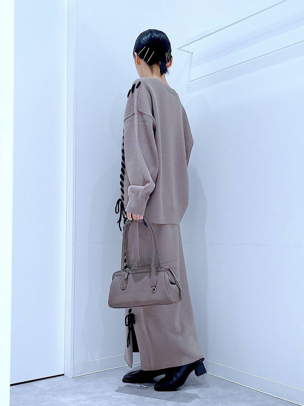 ブラウン系のニット/セーター、ブラウン系のスカート、ブラック系のブーツを着用したレディースの秋コーディネートの3枚目の写真