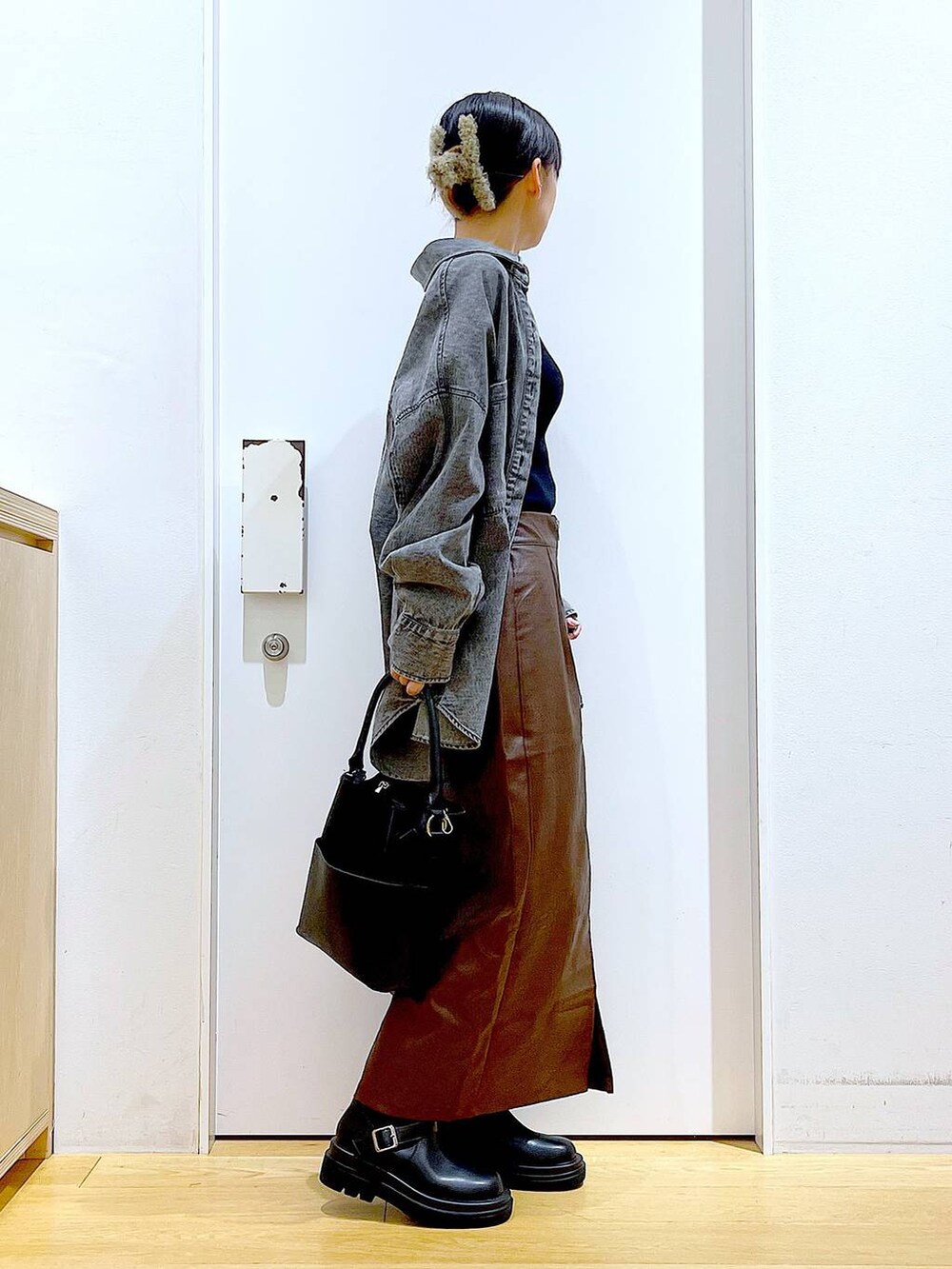 ブラウン系のスカート、ブラック系のニット/セーター、ブラック系のショルダーバッグを着用したレディースの秋コーディネートの4枚目の写真