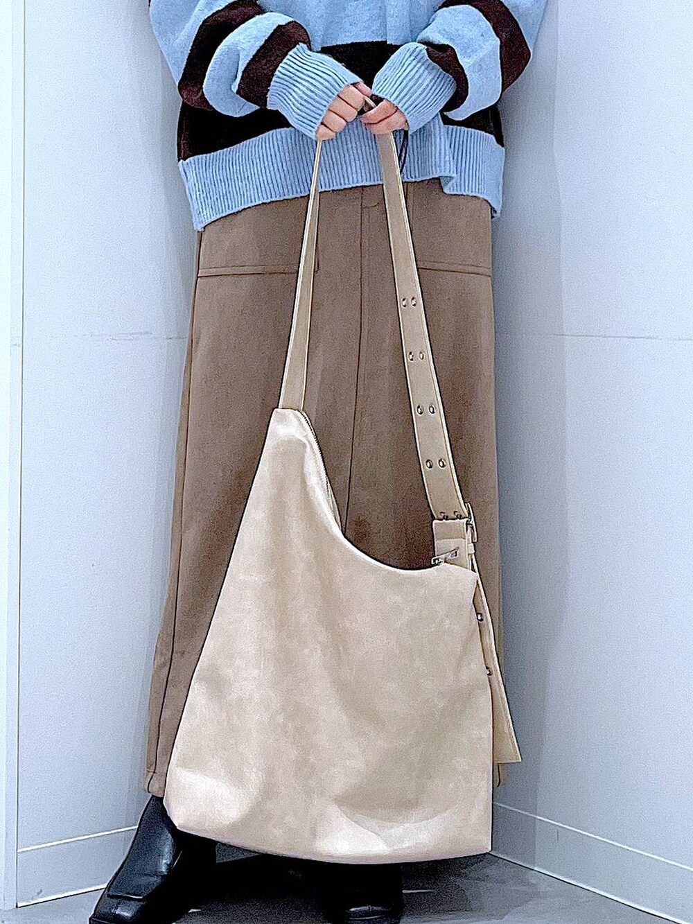 ブラック系のブーツ、ブラウン系のスカート、ブルー系のニット/セーターを着用したレディースの冬コーディネートの9枚目の写真