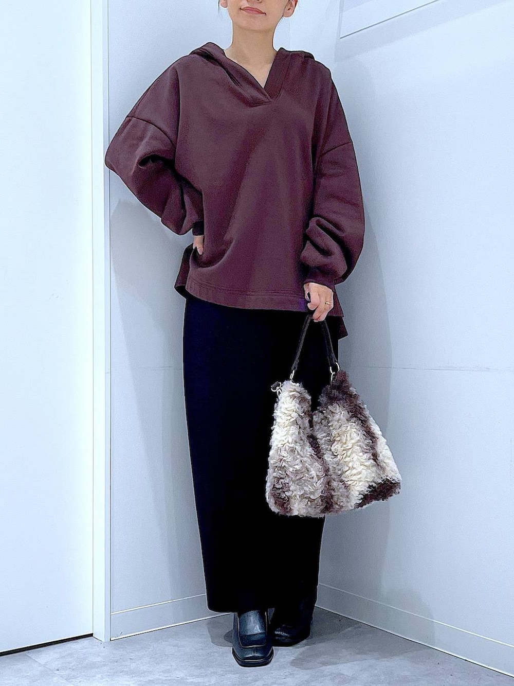 ブラック系のブーツ、ブラウン系のショルダーバッグ、ブラック系のスカートを着用したレディースの冬コーディネートの6枚目の写真