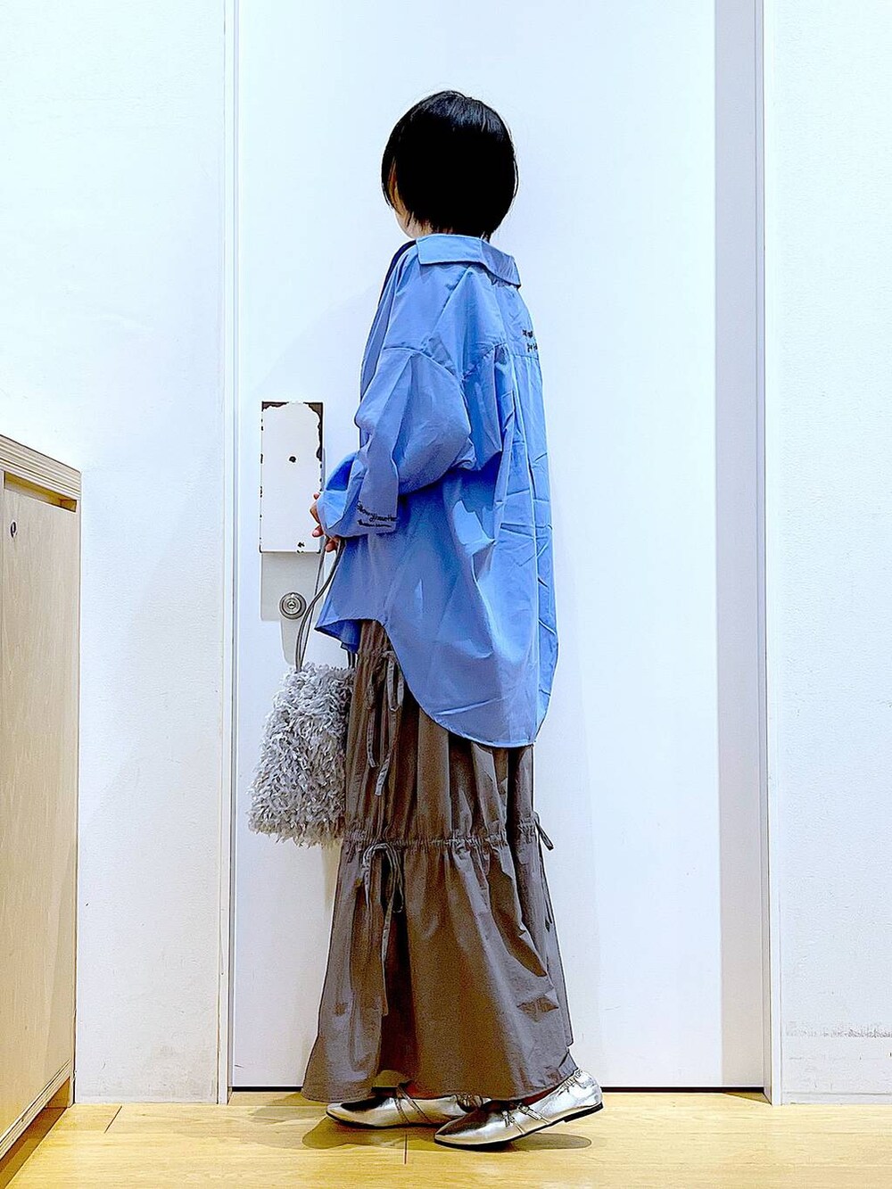 グレー系のショルダーバッグ、シルバー系のパンプス、グレー系のスカートを着用したレディースの秋コーディネートの3枚目の写真