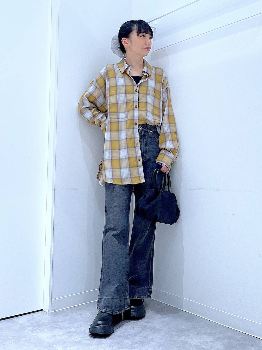 ブラック系のハンドバッグ、ブラック系のデニムパンツ、イエロー系のシャツ/ブラウスを着用したレディースの秋コーディネートの2枚目の写真