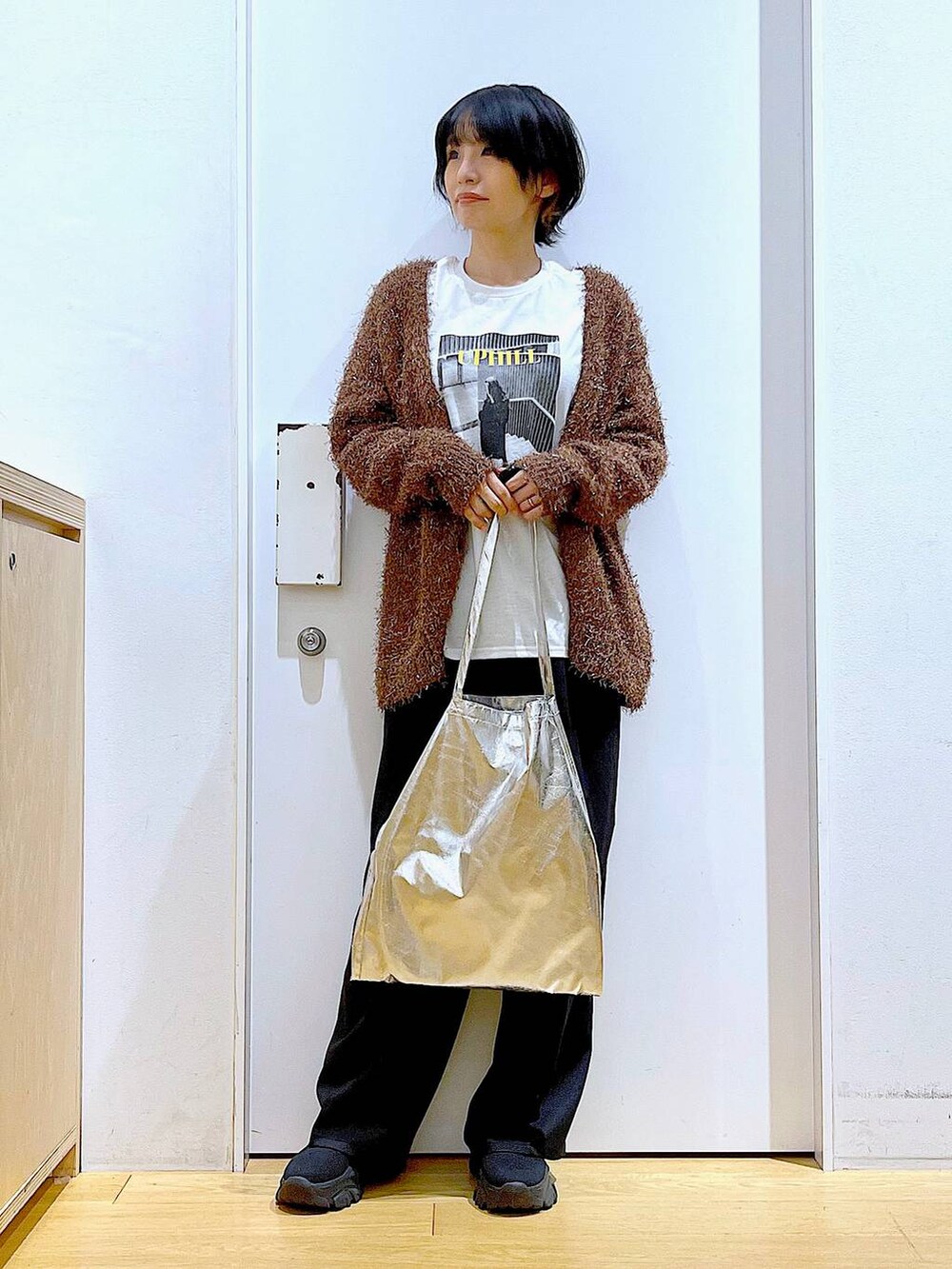 シルバー系のトートバッグ、ブラック系のスラックス、ホワイト系のTシャツ/カットソーを着用したレディースの秋コーディネートの2枚目の写真