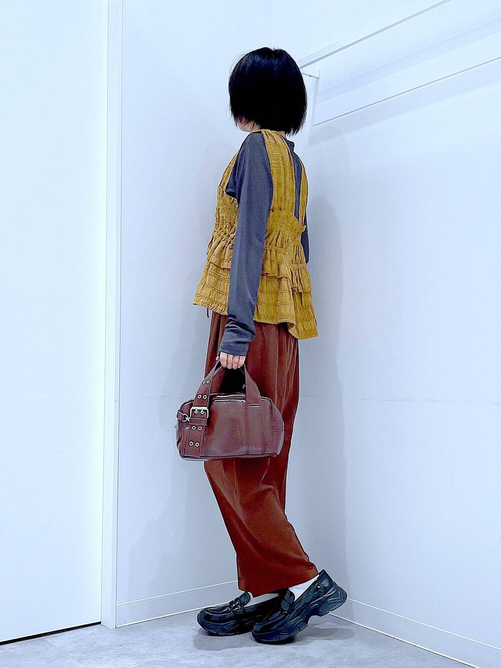 グレー系のTシャツ/カットソー、ブラック系のローファー、ブラック系のショルダーバッグを着用したレディースの秋コーディネートの3枚目の写真