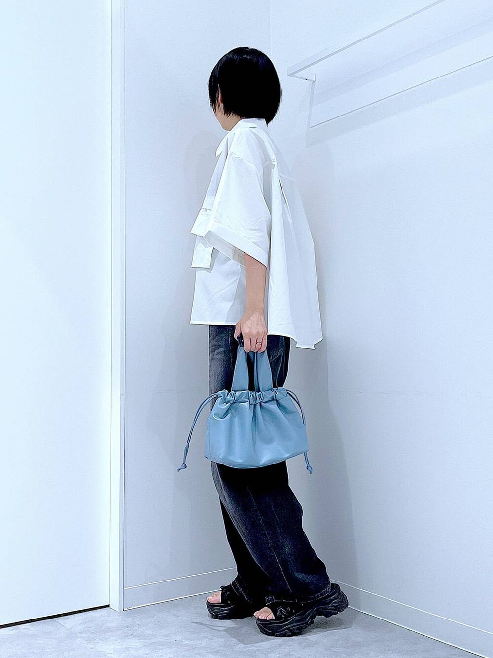 ブラック系のデニムパンツ、ブラック系のスニーカー、ブルー系のショルダーバッグを着用したレディースの夏コーディネートの3枚目の写真