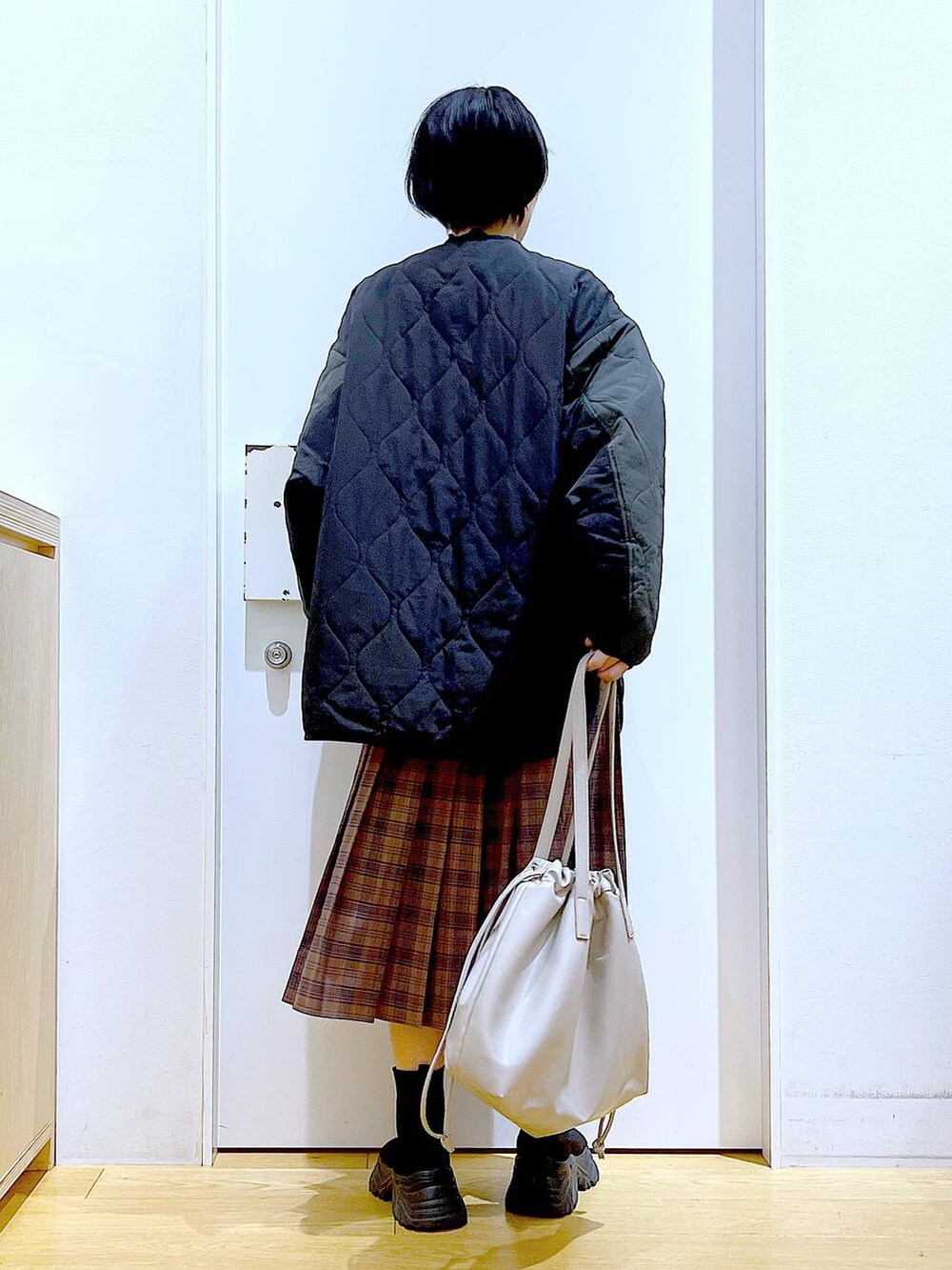 ベージュ系のトートバッグ、ブラック系のブルゾン、ブラック系のTシャツ/カットソーを着用したレディースの秋コーディネートの5枚目の写真