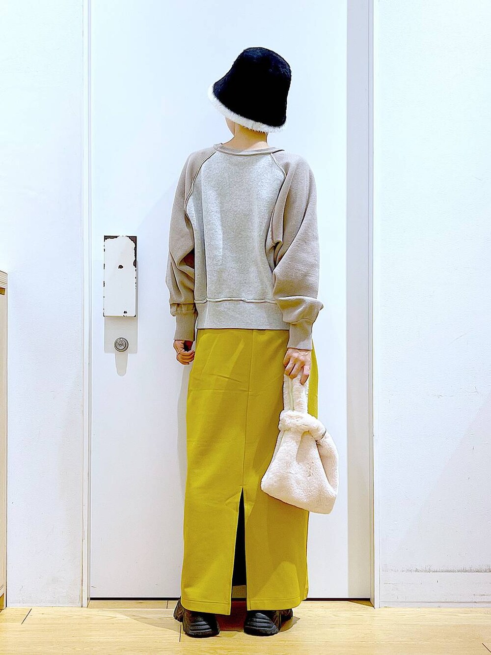 ホワイト系のショルダーバッグ、ブラック系のブーツ、ベージュ系のニット/セーターを着用したレディースの冬コーディネートの5枚目の写真