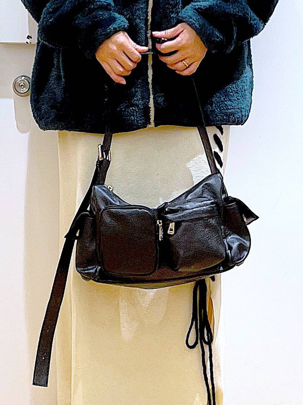 ブラック系のブーツ、ベージュ系のスカート、ブラック系のショルダーバッグを着用したレディースの冬コーディネートの9枚目の写真